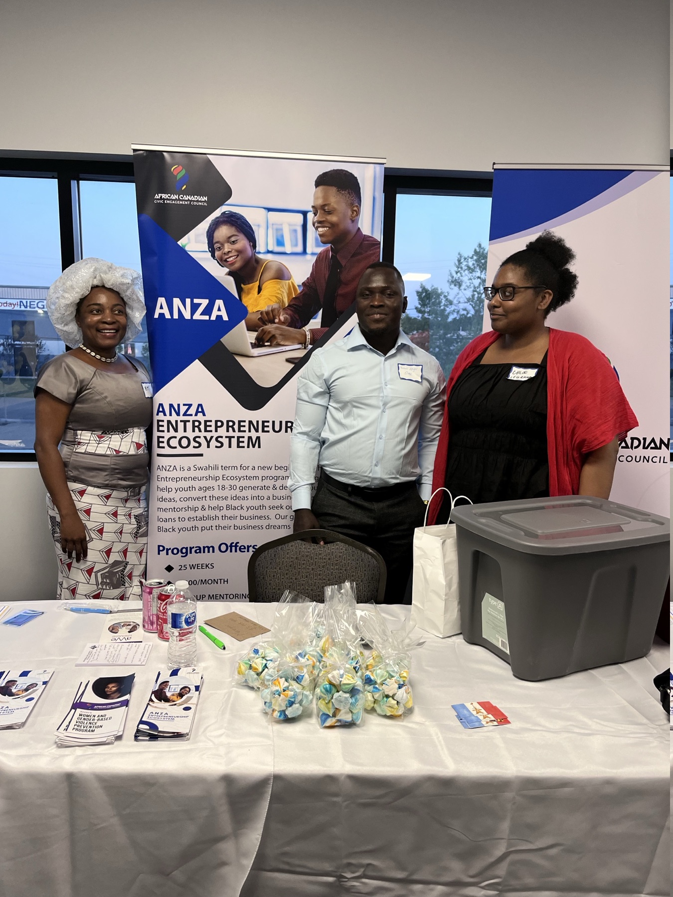 Three people standing behind an ANZA information table at a community showcase